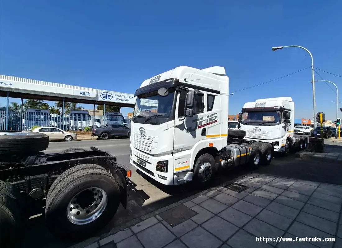 Tractocamión FAW JH6 460HP blanco con chasis expuesto y neumático de repuesto, vista lateral en calle urbana