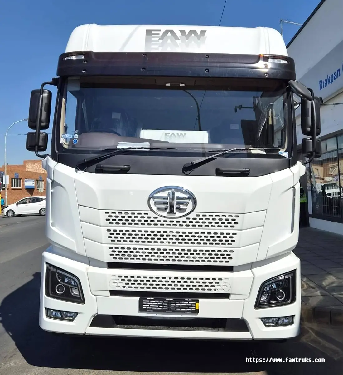 Tractocamión FAW JH6 blanco, vista frontal con parrilla tipo panal, logotipo FAW y visera parasol