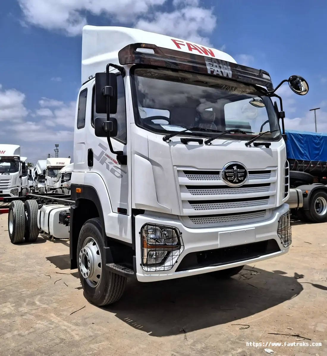 Camión FAW JK6 blanco con deflector aerodinámico y chasis vacío, vista frontal en patio de distribuidor