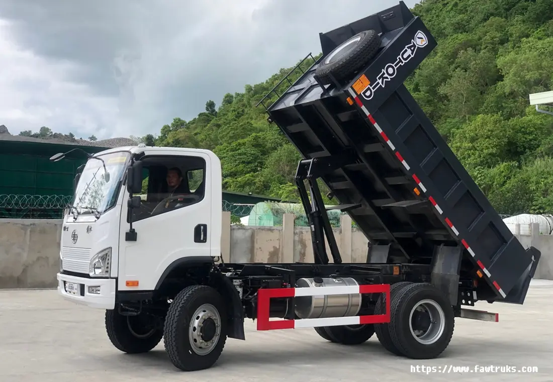 Camión volqueta FAW blanco con caja de volteo negra, vista frontal en patio industrial en Ecuador